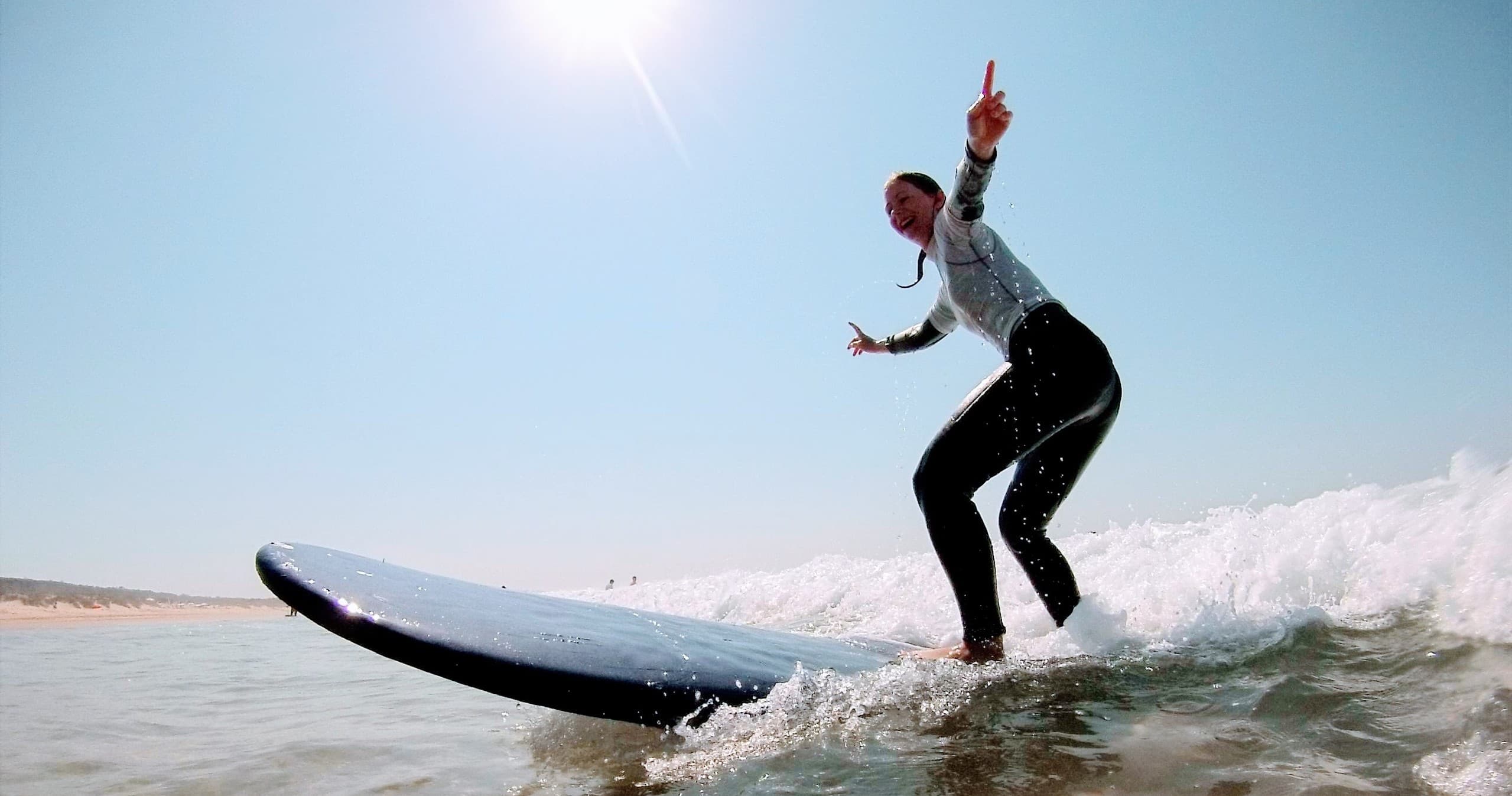 Surfer carving a wave under bright sun on open ocean beach