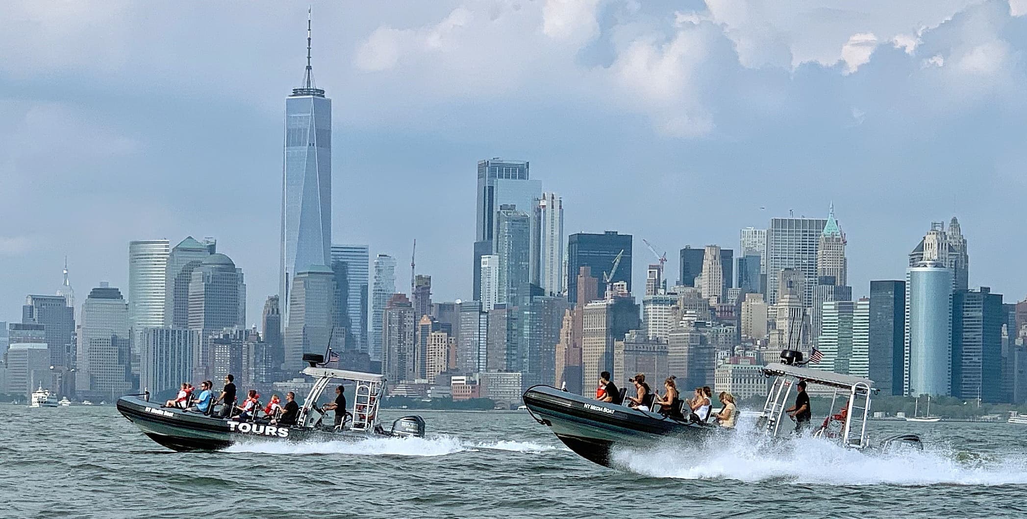 Two RIBs racing past Lower Manhattan skyline on water tour