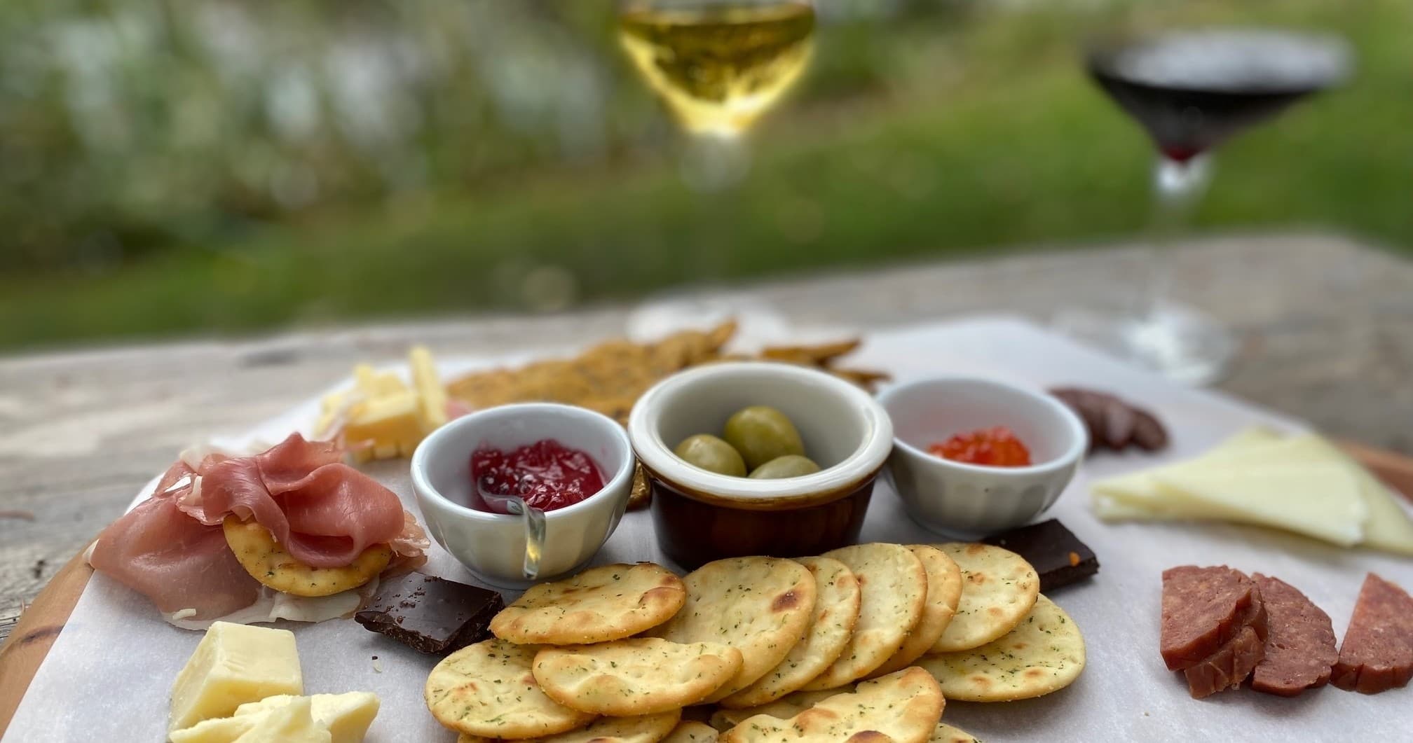 Outdoor charcuterie and wine picnic on rustic farm table