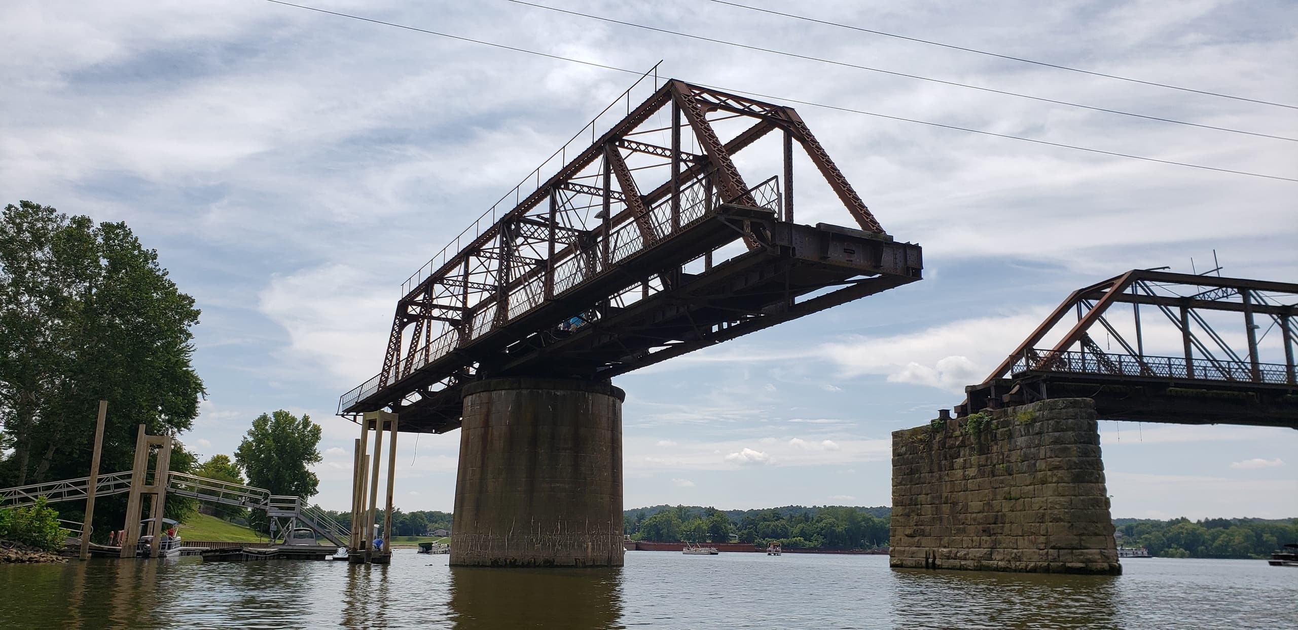 Historic swing railroad bridge spanning river with exposed piers and sky