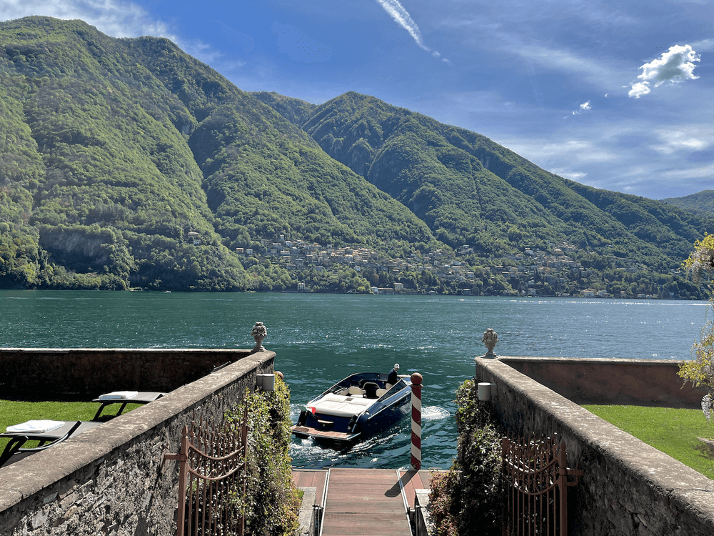 Stone steps leading to Lake Como dock with boats and mountains