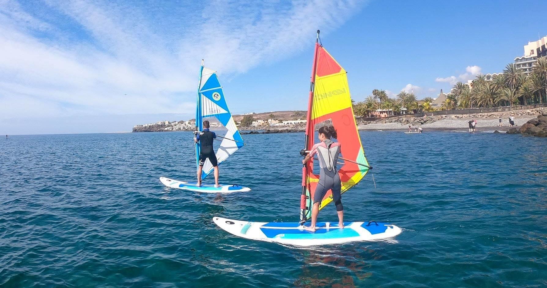 Two windsurfers sailing together on turquoise Atlantic off Gran Canaria