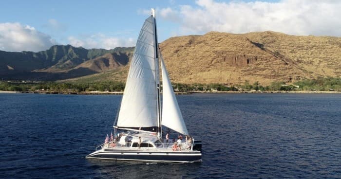 Sailboat cruising clear blue Pacific waters with island backdrop
