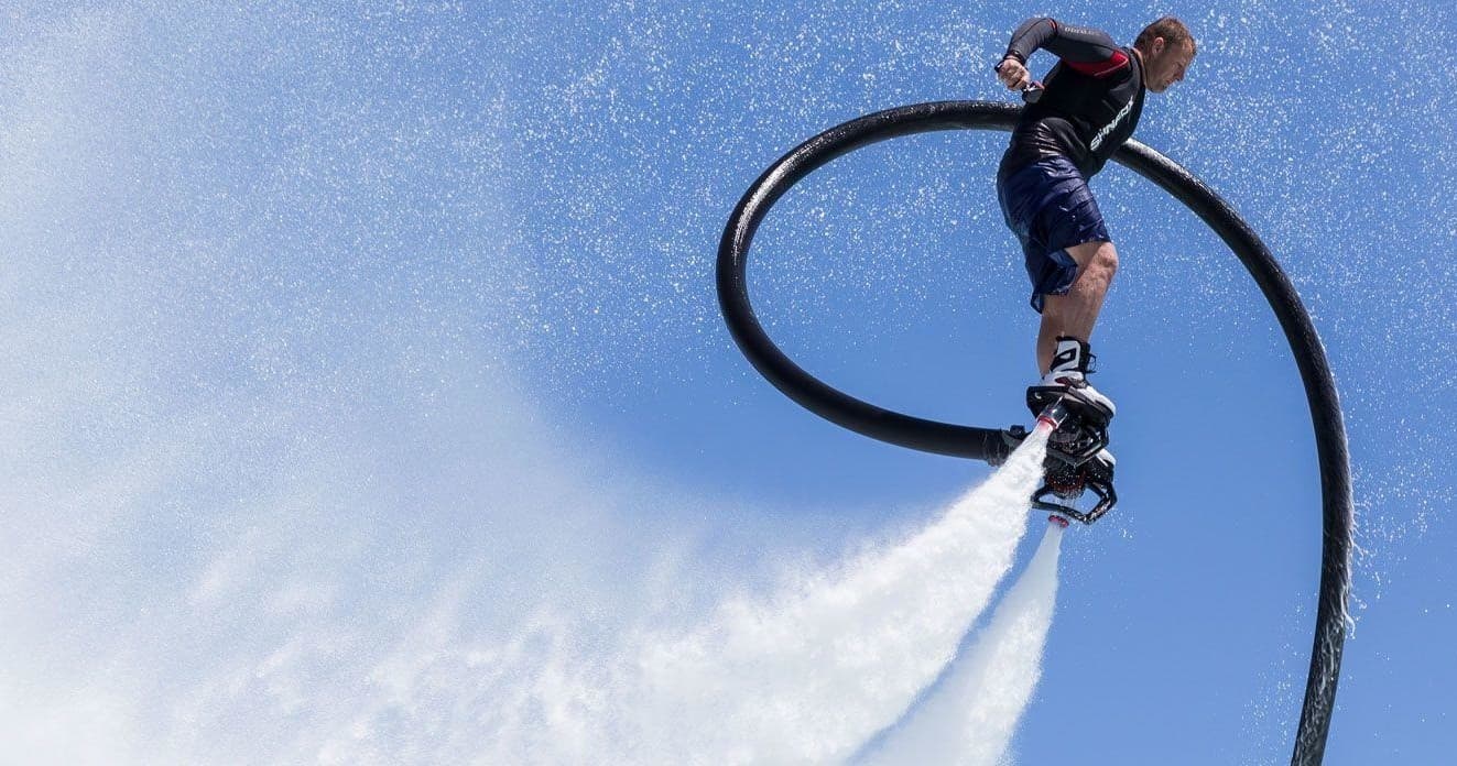 Flyboarder performing aerial stunt over open blue ocean and sky