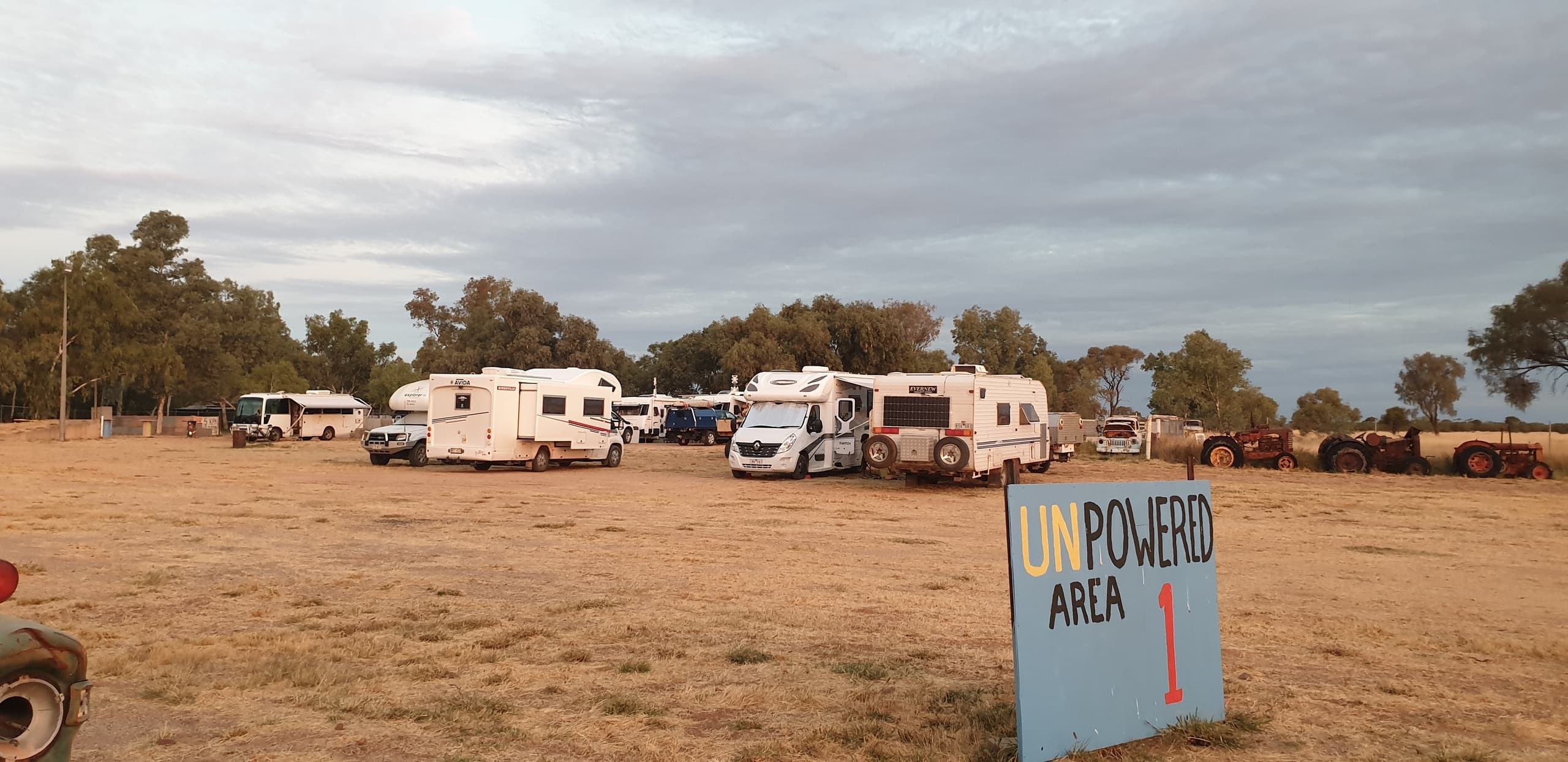 Caravans parked at open outback campground under cloudy sky