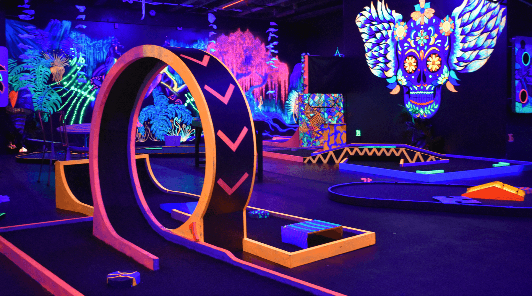 Indoor glow-in-the-dark mini golf course with neon obstacles