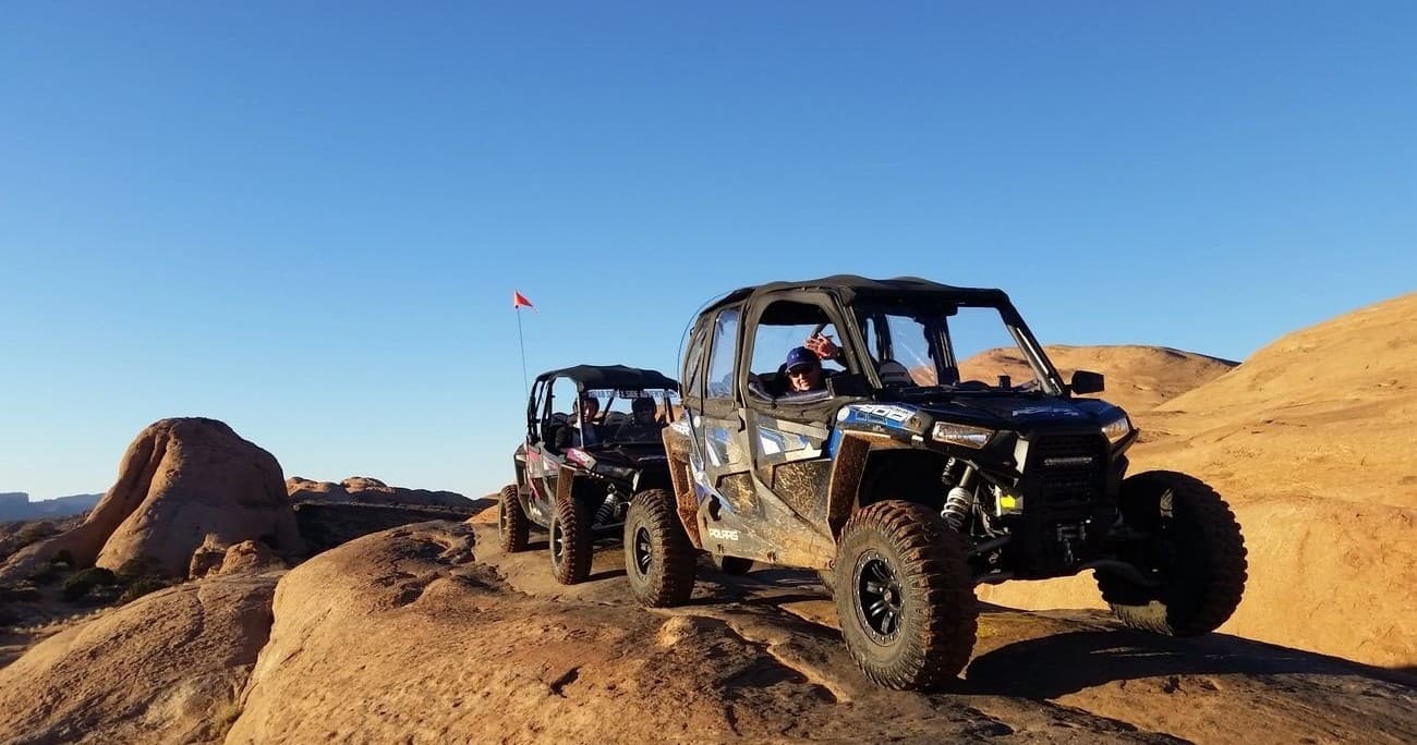 Group of side-by-side UTVs on red rock trail in Moab desert