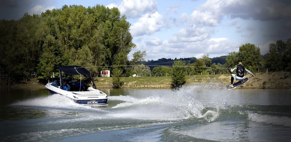Two speedboats creating large wakes on scenic freshwater lake