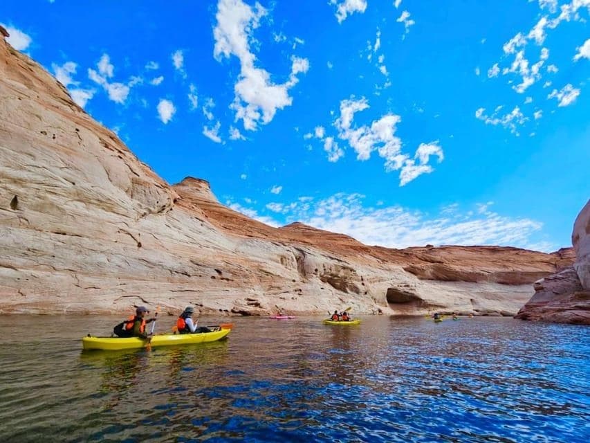 Kayakers paddling through desert canyon lake under blue sky
