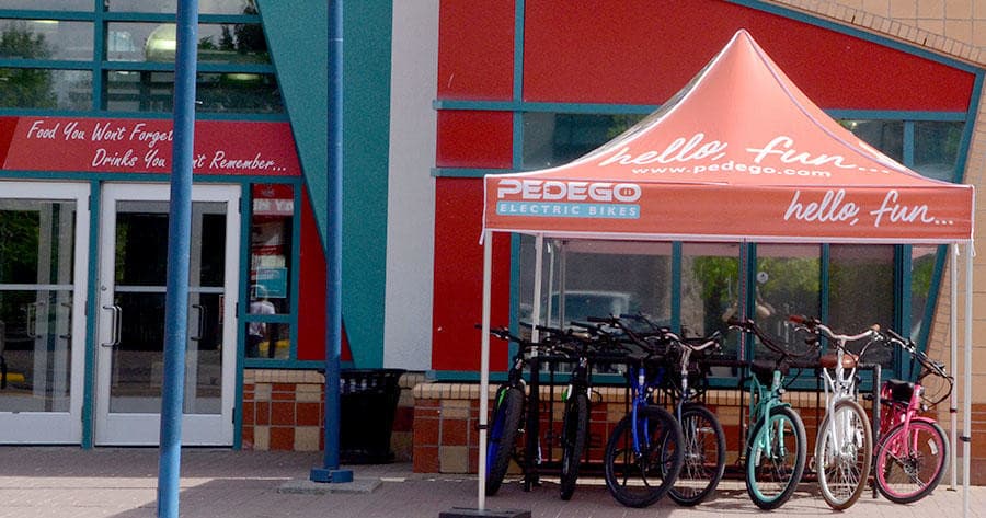 Bike shop storefront with tent display and rental e-bikes outside