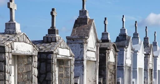 Row of historic above-ground cemetery tombs under blue sky