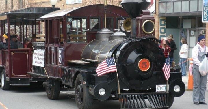 Vintage tourist train driving down a small town main street