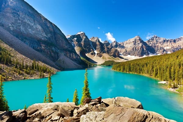 Panoramic turquoise lake with rocky foreground and peaks