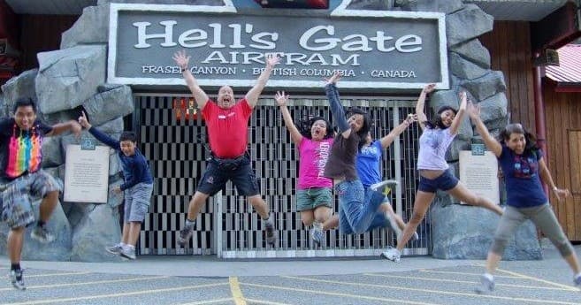 Visitors jumping in front of Hell's Gate Airtram entrance sign