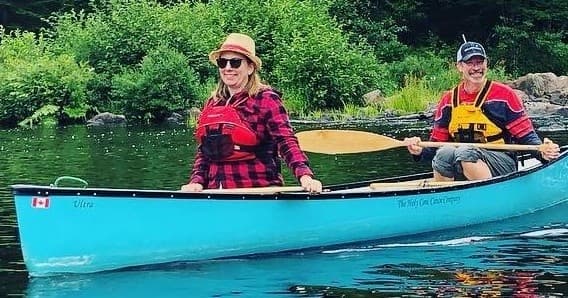 Couple canoeing on calm forest lake, paddling summer canoe trip