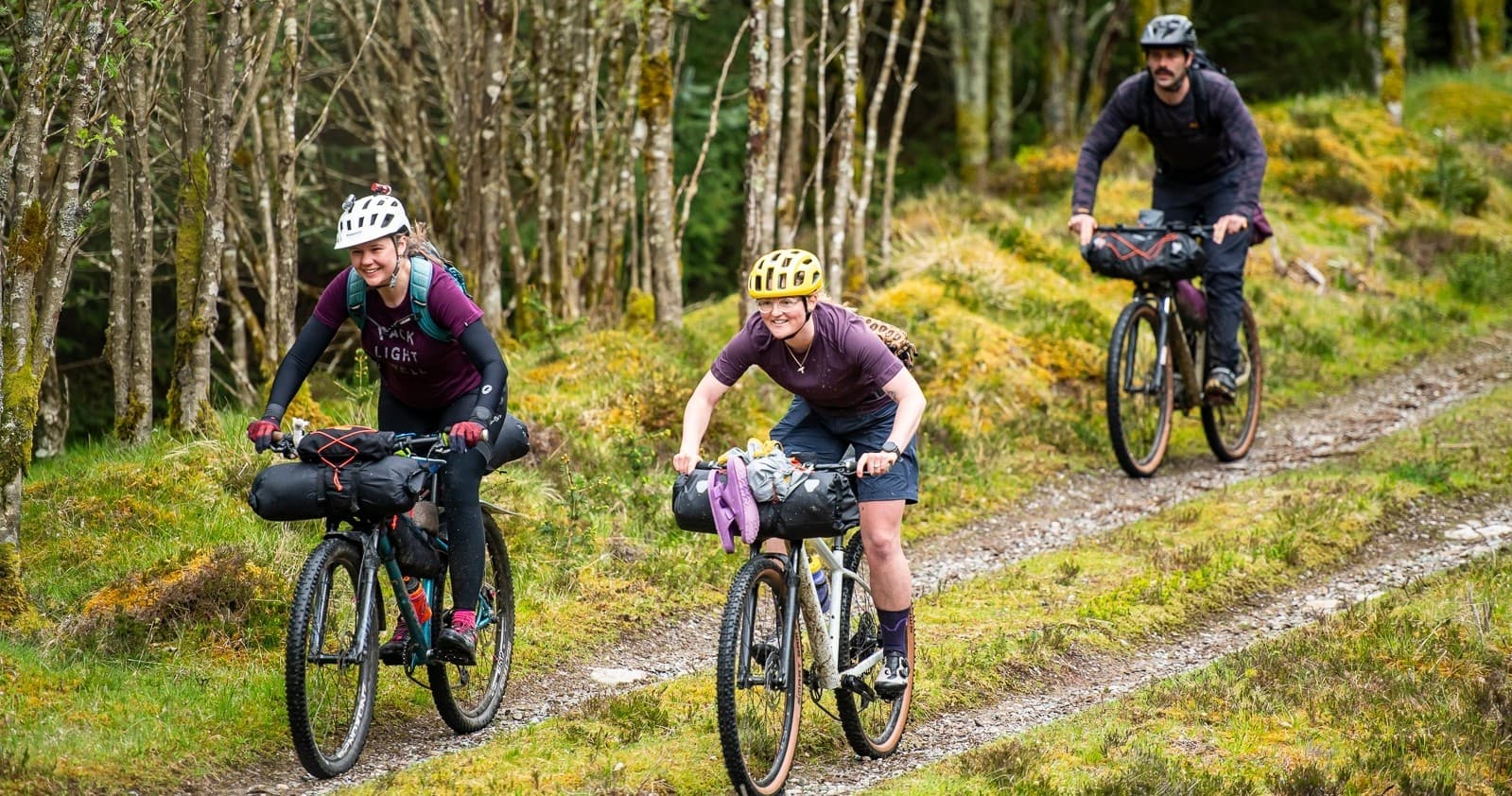 Cycle tourers riding forested gravel track with panniers