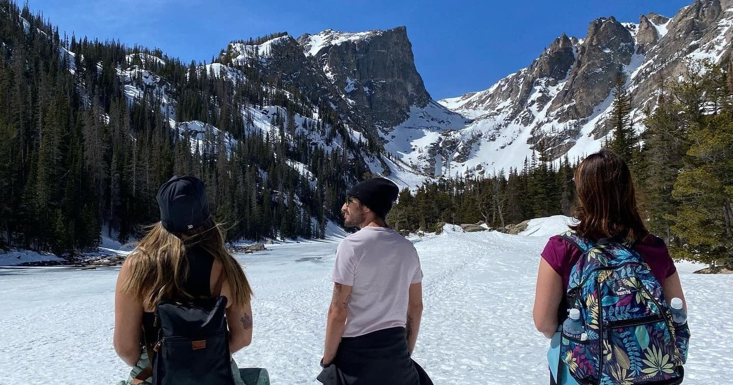 Three hikers viewing alpine lake and mountain valley scenery