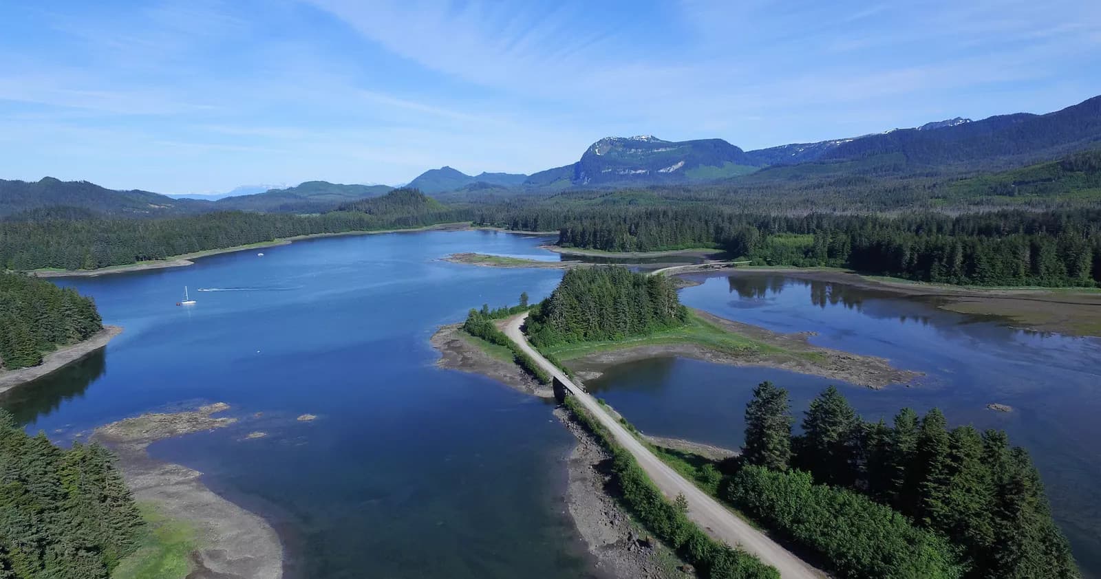 Aerial lake and mountain vista with scenic coastal bridge