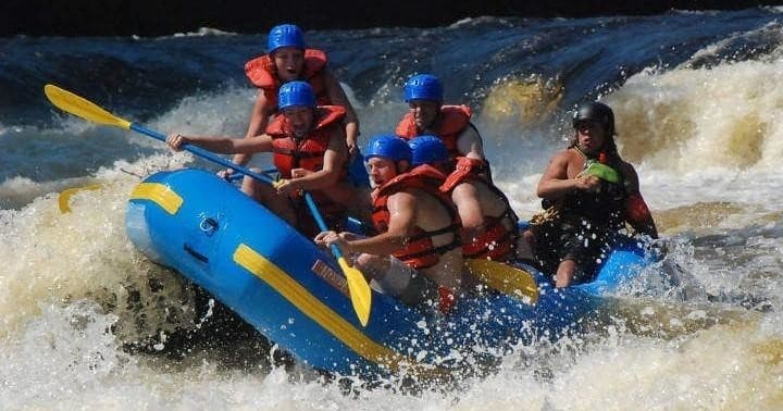 Group whitewater rafting team tackling turbulent river rapids