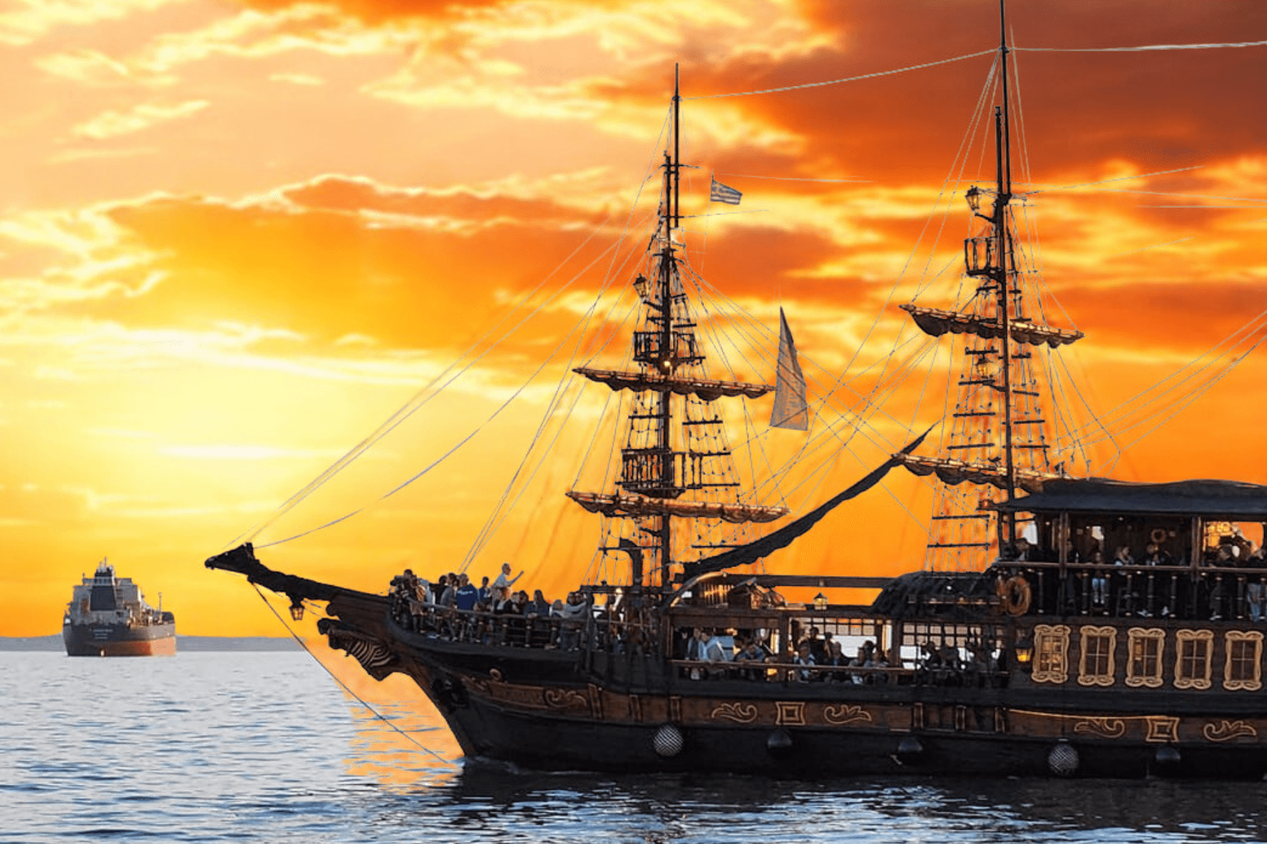 Tall ship sailing at sunset on open sea with passengers aboard