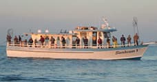 Crowded charter fishing boat on open ocean with anglers