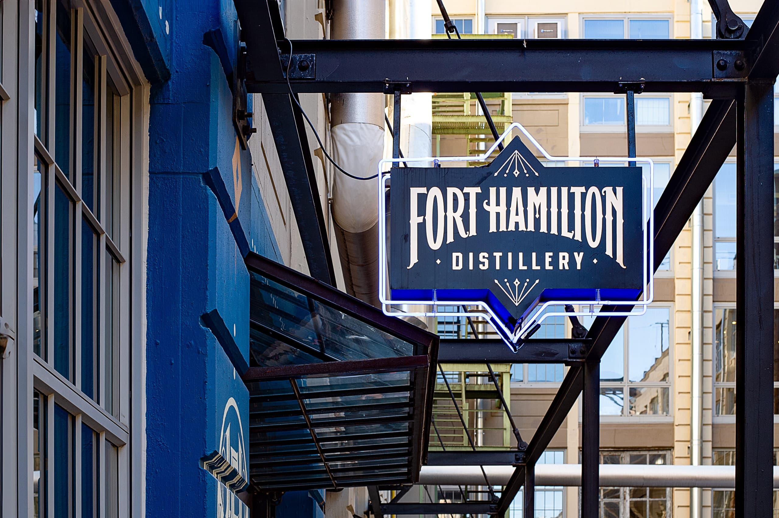 Fort Hamilton Distillery blue sign on urban alley entrance, storefront