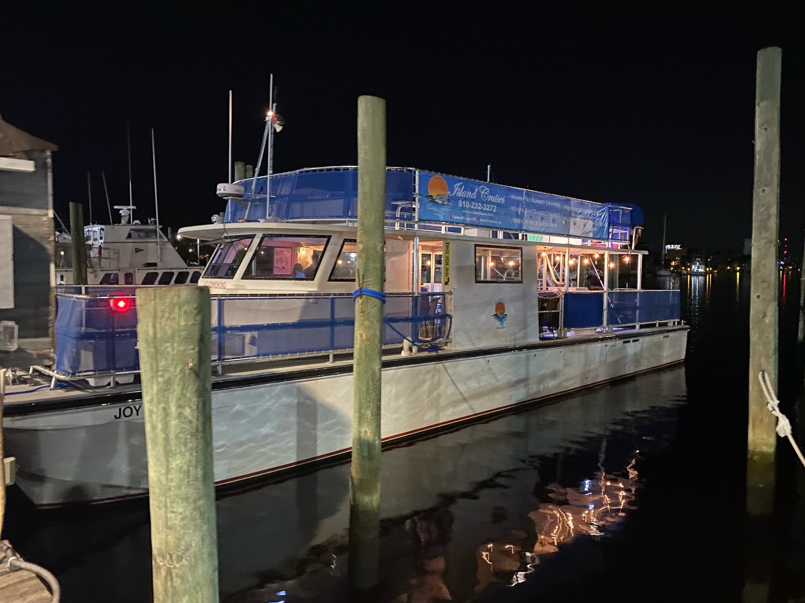 Docked sightseeing boat at night with harbor reflection
