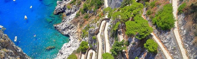 Aerial coastal view of winding cliff road and turquoise bay coastline