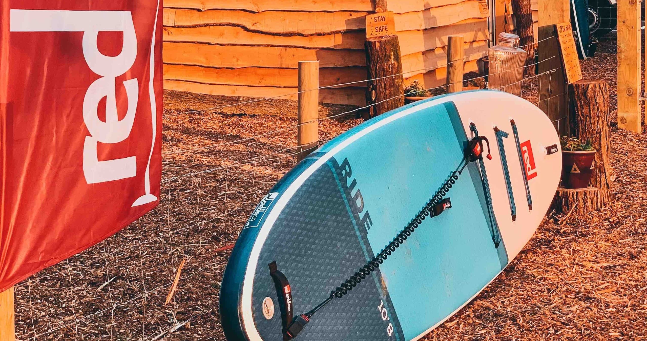 SUP boards resting against lakeside cabin gear display at sunset