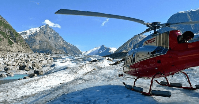 Helicopter landing on glacial ice amid Alaskan mountain vistas