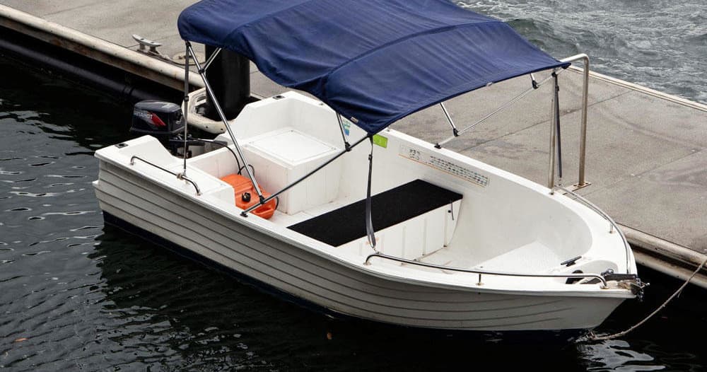 Small white motorboat with canopy docked at quiet marina