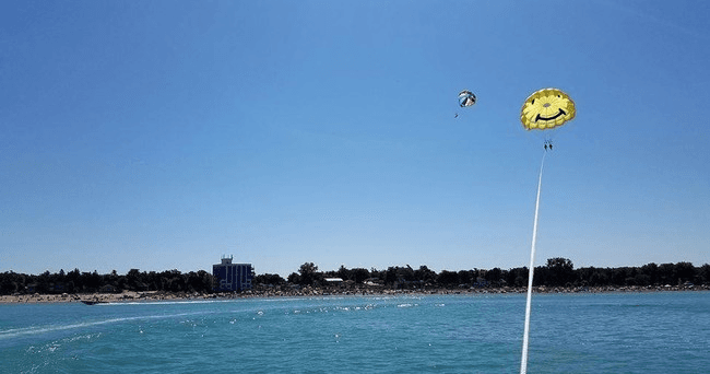 Parasailers flying over clear lake waters with blue sky