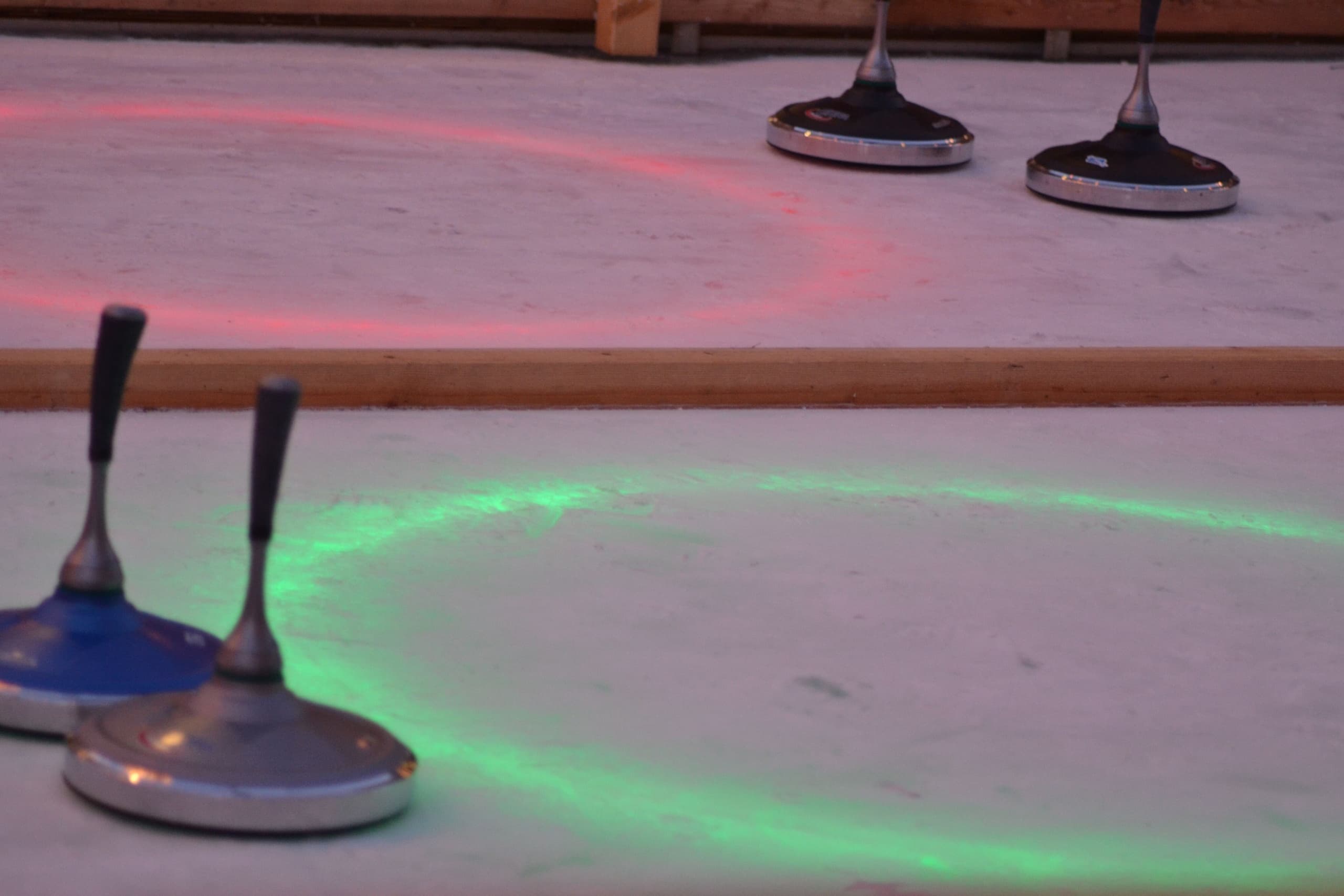 Curling stones on lit ice rink at seasonal holiday ice venue