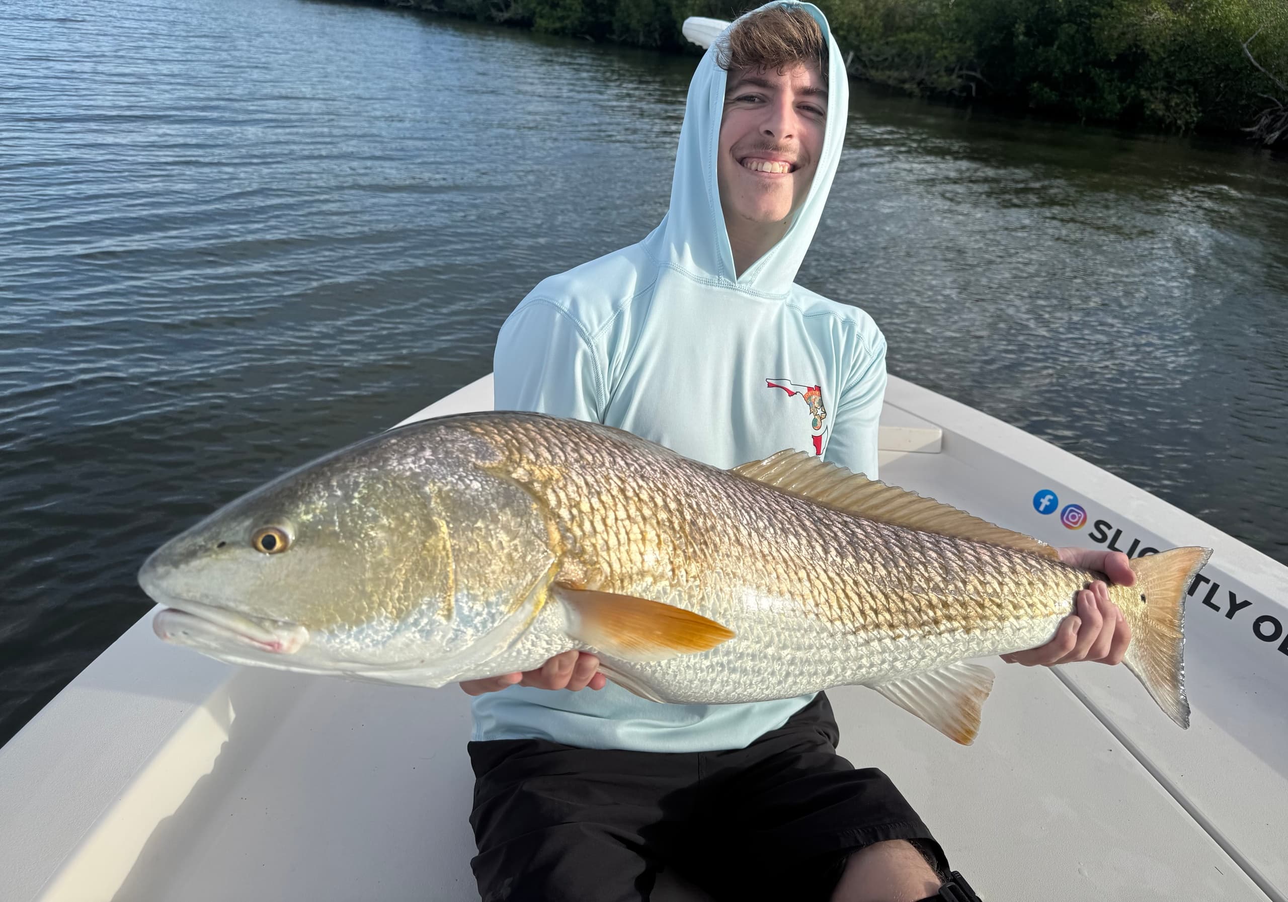 Angler posing with redfish on shallow coastal backwater fishing trip