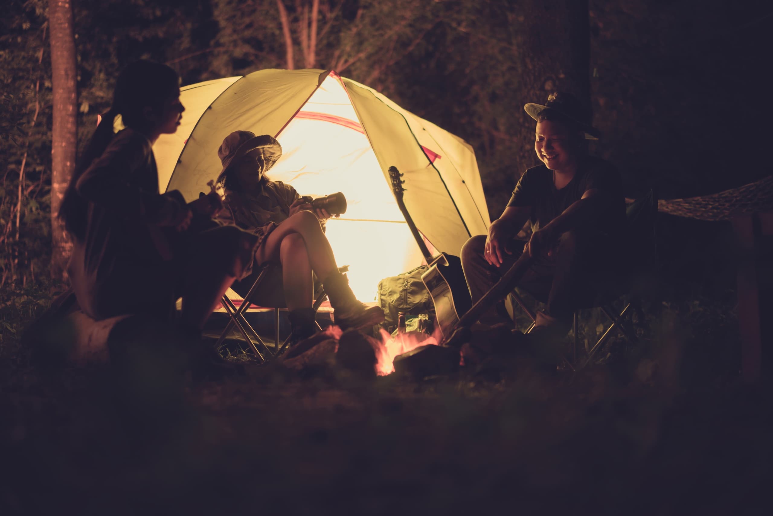 Group camping by tent and campfire in forest at Congo Preserve