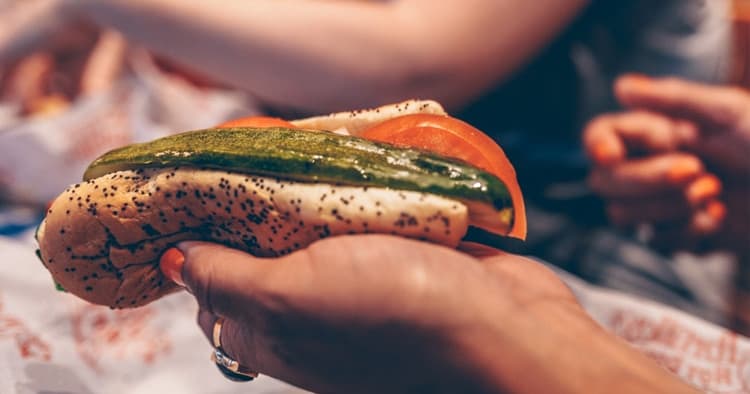 Handheld Chicago-style hot dog with poppy bun at street food stall