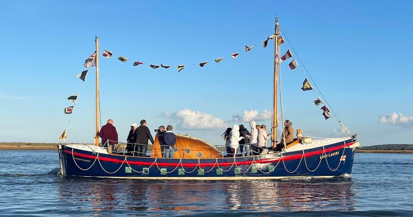 Passengers on decorated wooden rescue boat on calm coastal waters