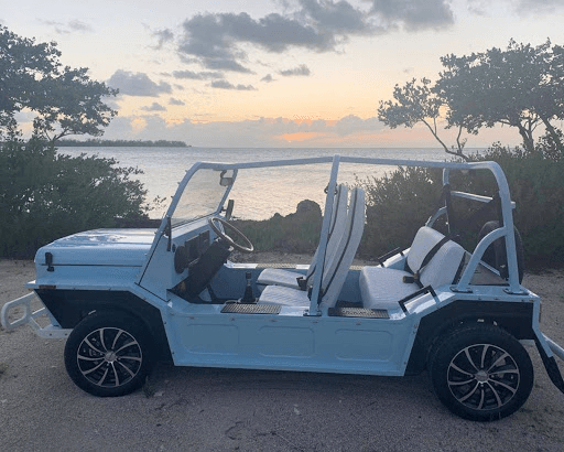 Coastal open-top moke driving along sunset ocean road