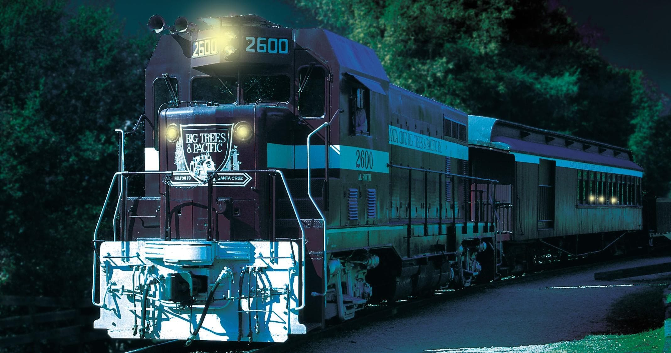Diesel locomotive passing through wooded landscape at dusk