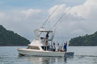 Sportfishing boat cruising near tropical island coastline, anglers