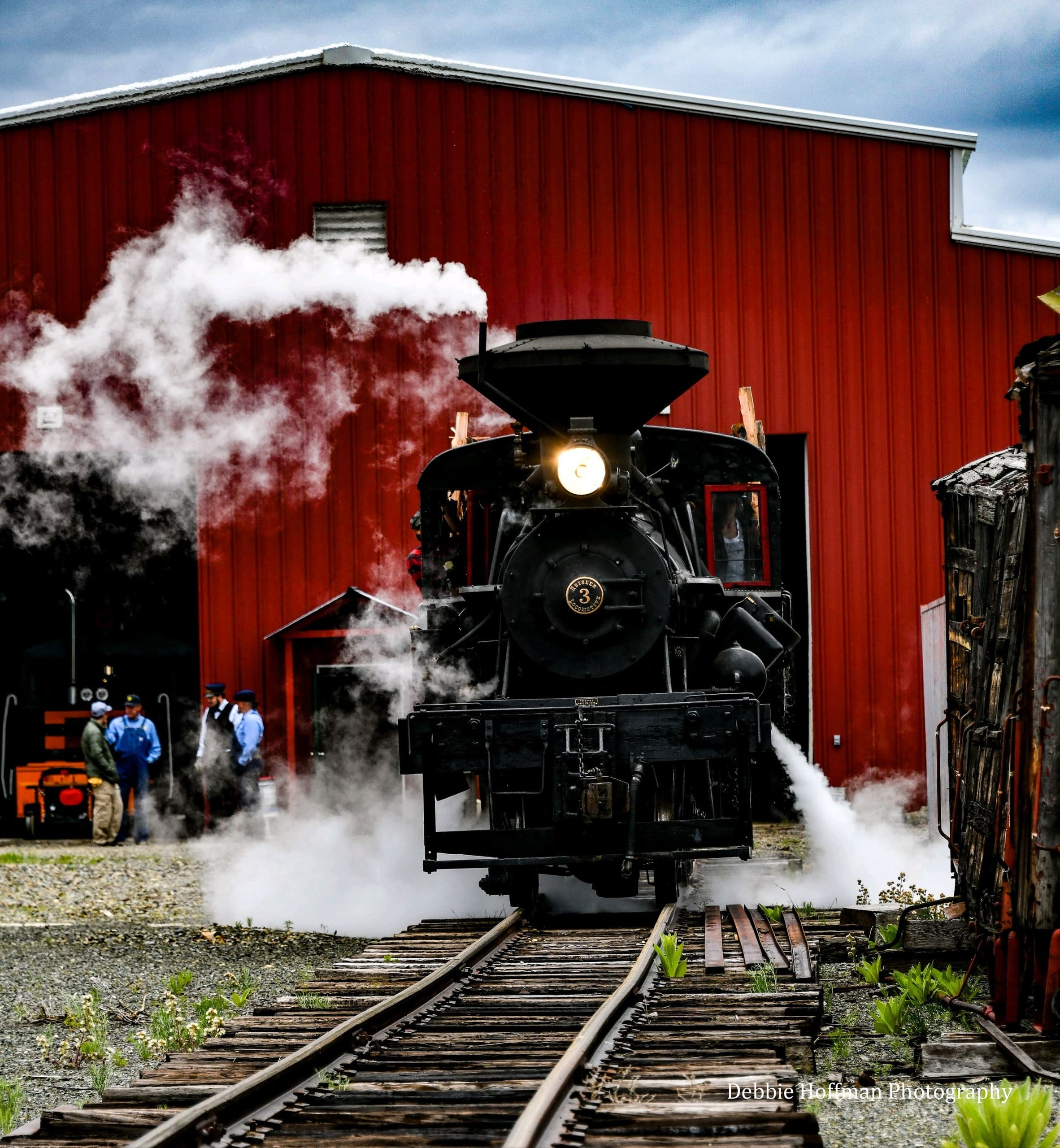 Steam train departing Sumpter Valley Railroad yard past red barn