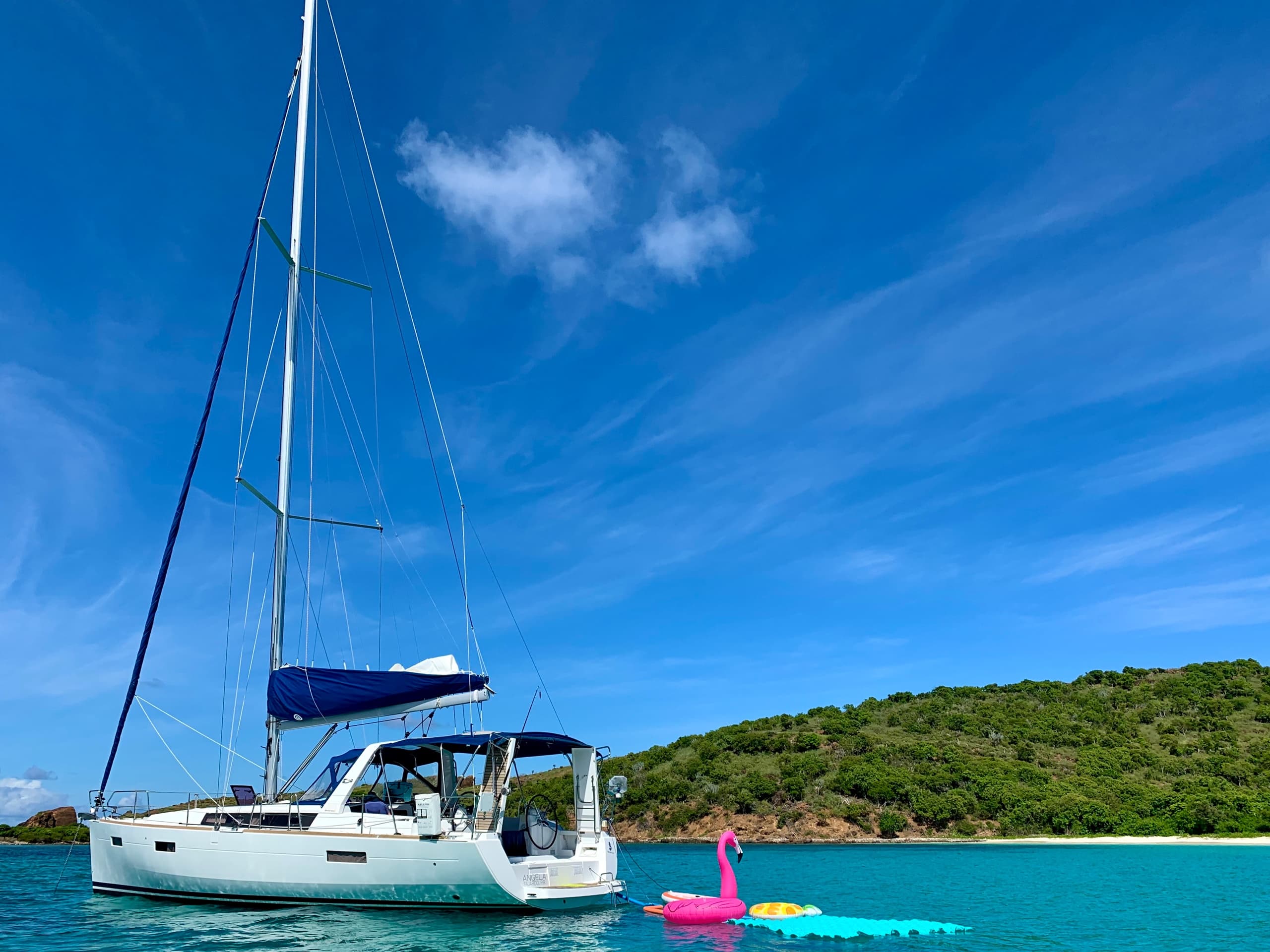 Anchored catamaran in turquoise lagoon with flamingo float