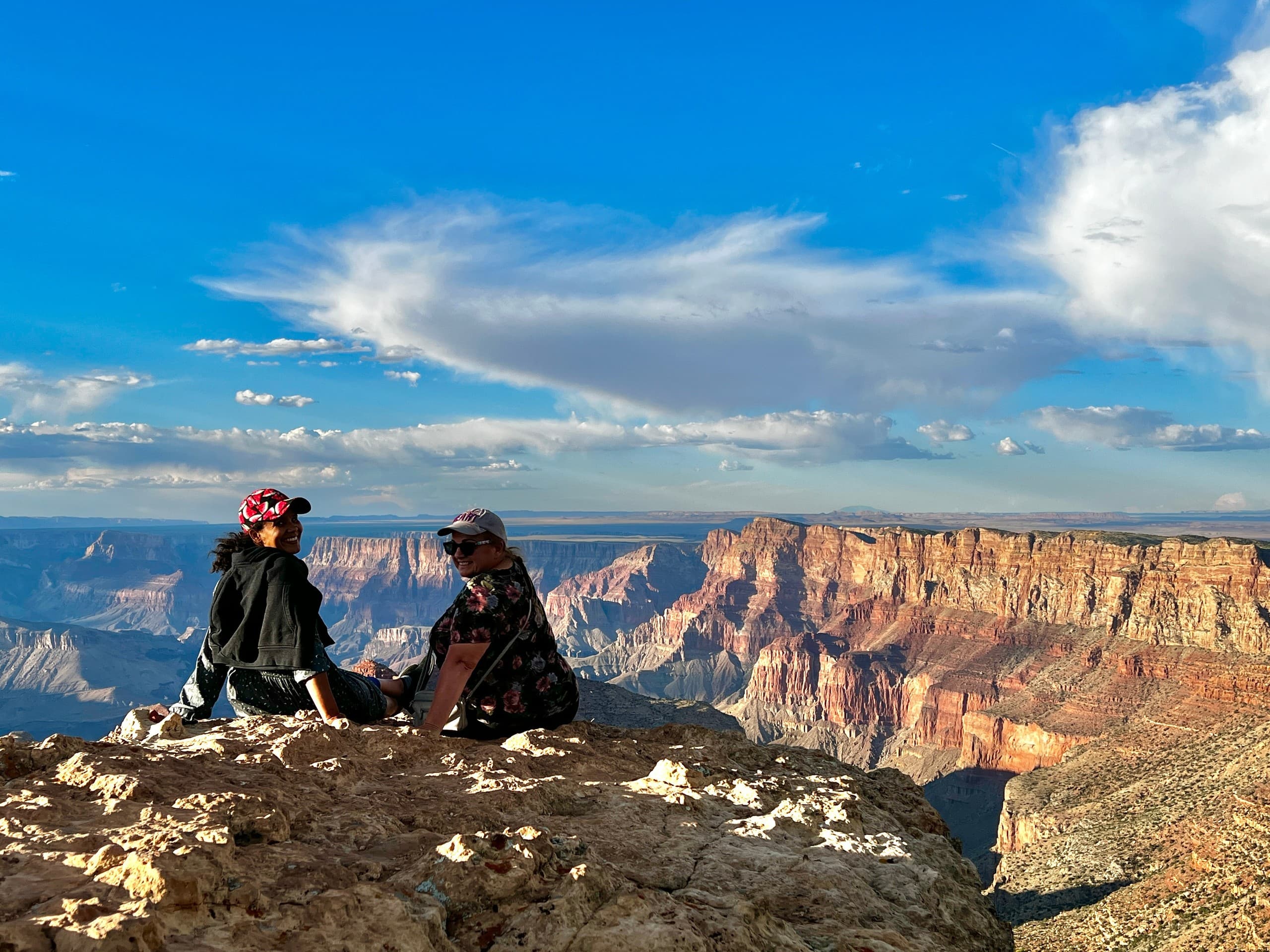 Hikers seated on cliff overlooking Grand Canyon sunrise views