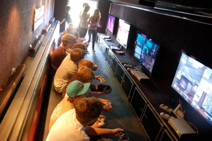 Kids playing console games inside mobile game trailer interior