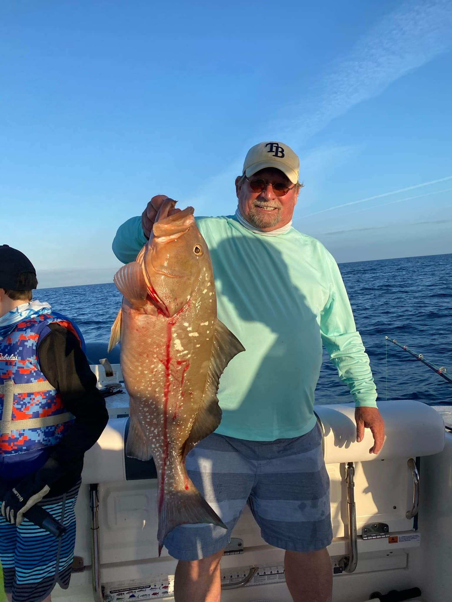 Fisherman holding large reef grouper on offshore deep-sea trip