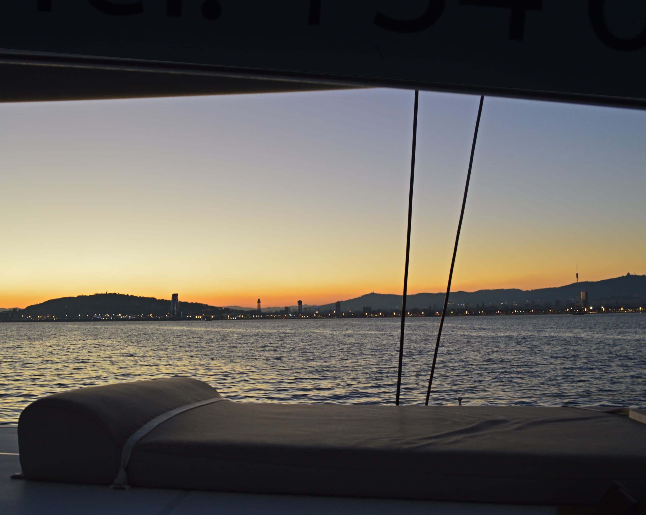 Sunset sailboat view over calm bay toward city skyline
