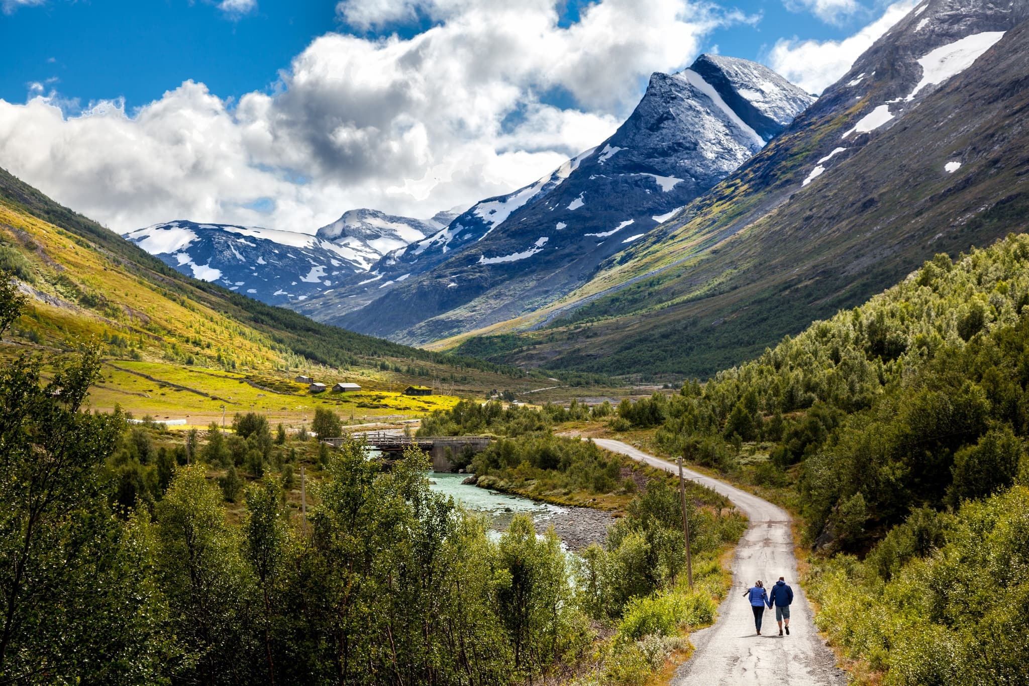 Hikers walking alpine valley trail with dramatic mountain peaks