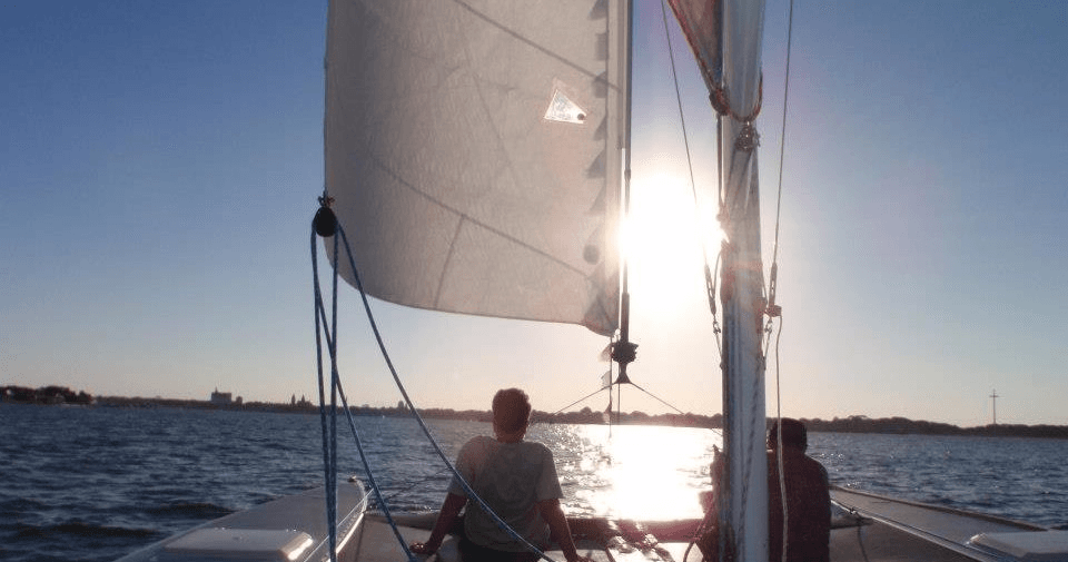 Sailboat cruising at sunset with crew on open coastal water