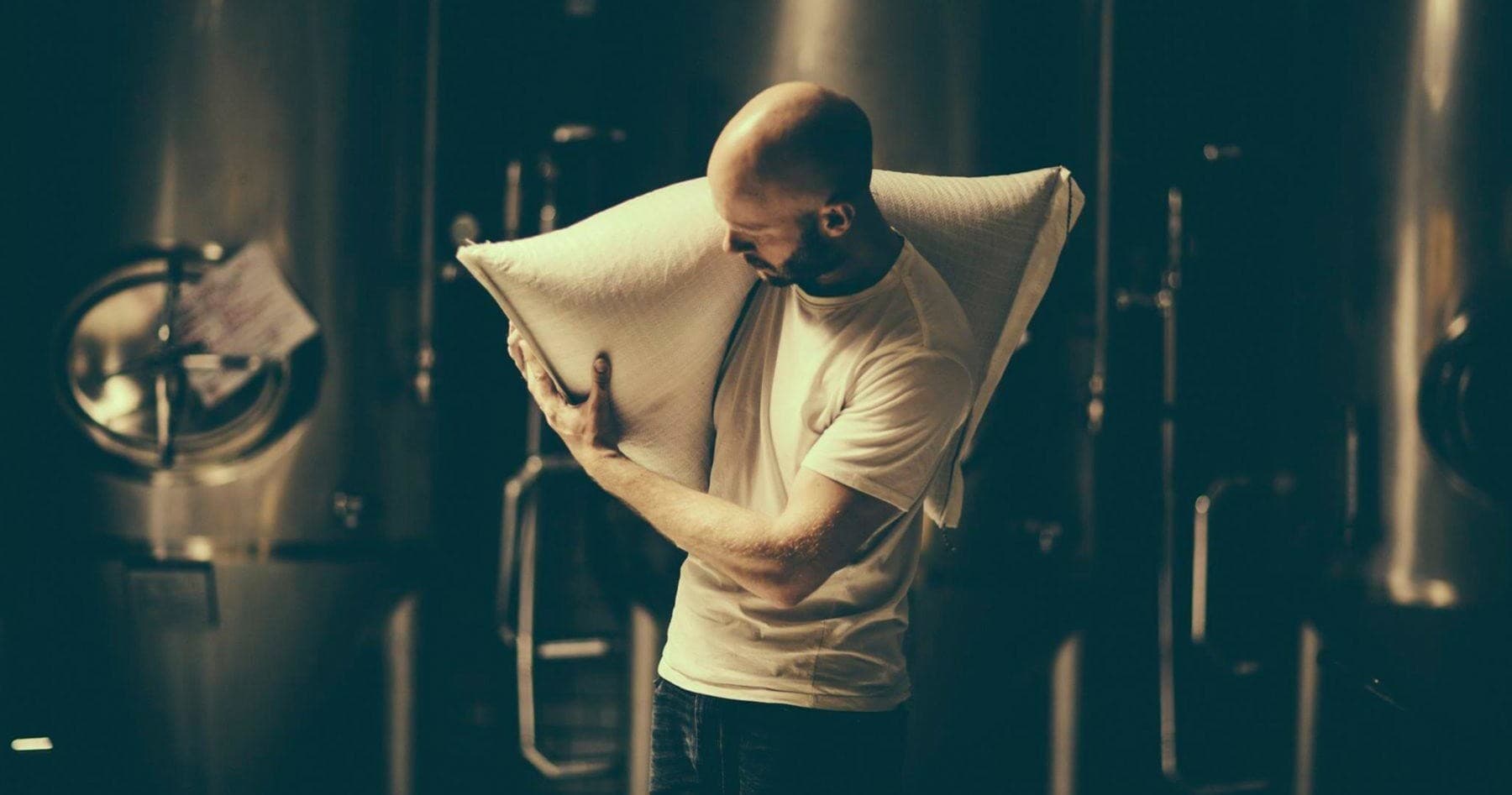 Brewer inspecting grain sacks in industrial brewery production