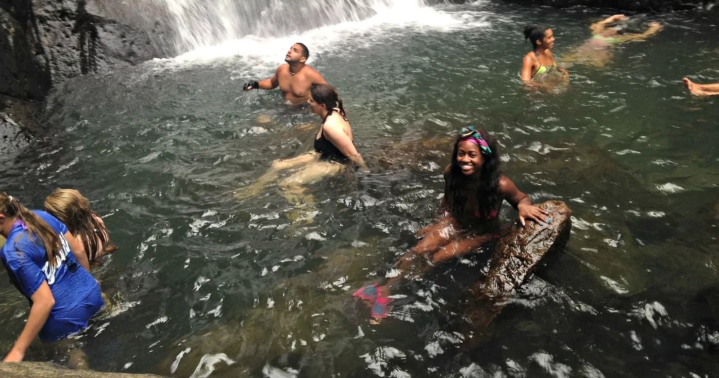 People swimming in a natural waterfall pool during adventure swim